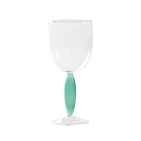 Copa transparente con tallo decorativo verde esmeralda brillante sobre fondo blanco neutro.