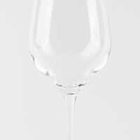 Calice à vin transparent en verre avec long pied sur fond blanc uniforme.