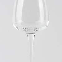 Vaso transparente de cristal con tallo fino sobre fondo gris claro uniforme