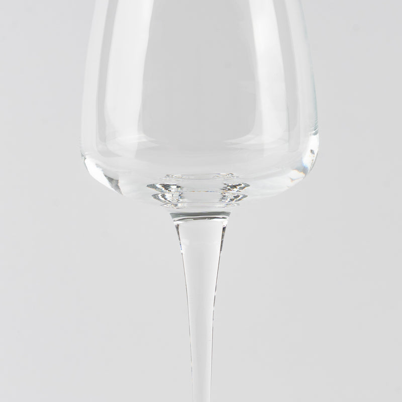 Vaso transparente de cristal con tallo fino sobre fondo gris claro uniforme