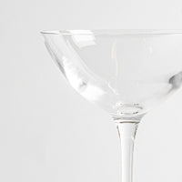 coupe à cocktail en verre transparent avec pied fin sur fond blanc