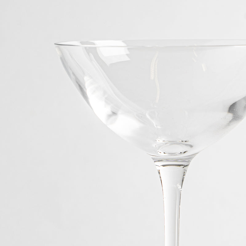 coupe à cocktail en verre transparent avec pied fin sur fond blanc
