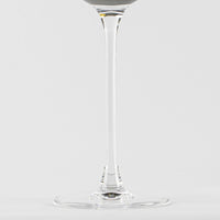 Verre transparent en verre avec tige fine et base ronde sur fond blanc uniforme
