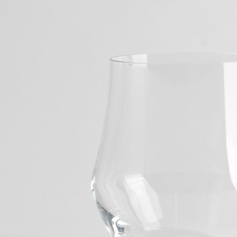 Transparentes Glas mit breiter Basis und leicht schmalerer Öffnung auf schlichtem weißem Hintergrund.