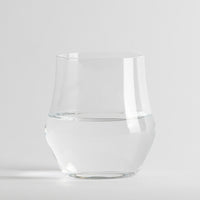 Transparentes Glas mit Wasser, neutraler weißer Hintergrund und Oberfläche.