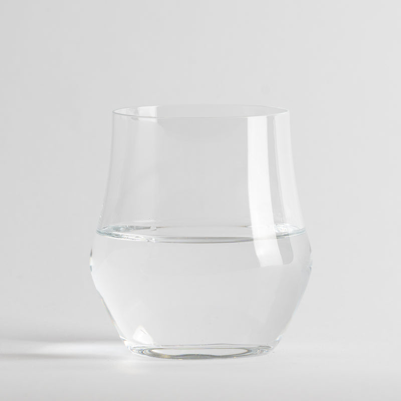 Transparentes Glas mit Wasser, neutraler weißer Hintergrund und Oberfläche.