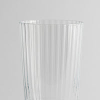 Transparant glas met verticaal geribbeld oppervlak op uniforme grijze achtergrond.