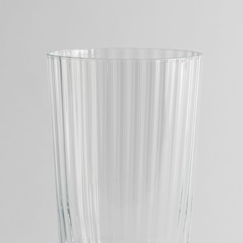 Transparant glas met verticaal geribbeld oppervlak op uniforme grijze achtergrond.