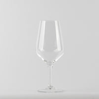 Transparent glass tumbler a stemmed glass with thin stem on light gray background