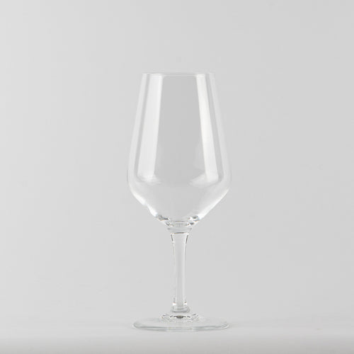 Transparent glass tumbler a stemmed glass with thin stem on light gray background