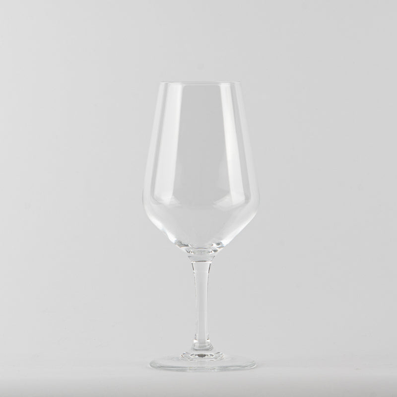 Transparent glass tumbler a stemmed glass with thin stem on light gray background