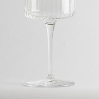 transparent glass tumbler with long stem and stemmed glass decorated with righe verticali on white background