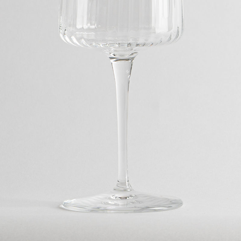 transparent glass tumbler with long stem and stemmed glass decorated with righe verticali on white background