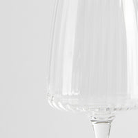 Transparent glass wine glass with ribbed surface on neutral white background.