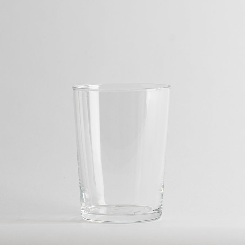 Vaso transparente de cristal con forma cilíndrica, sobre fondo gris claro uniforme