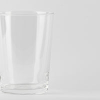 Vaso transparente de cristal con borde redondeado sobre fondo blanco uniforme