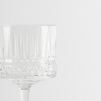 Copa de vidrio transparente con motivos geométricos sobre fondo blanco minimalista