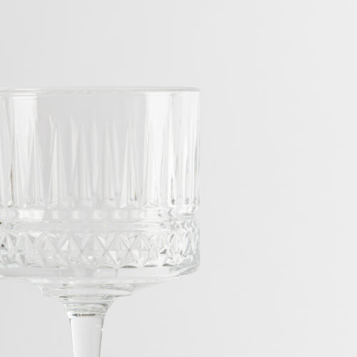 bicchiere di vetro trasparente a calice con motivi geometrici su sfondo bianco minimalista