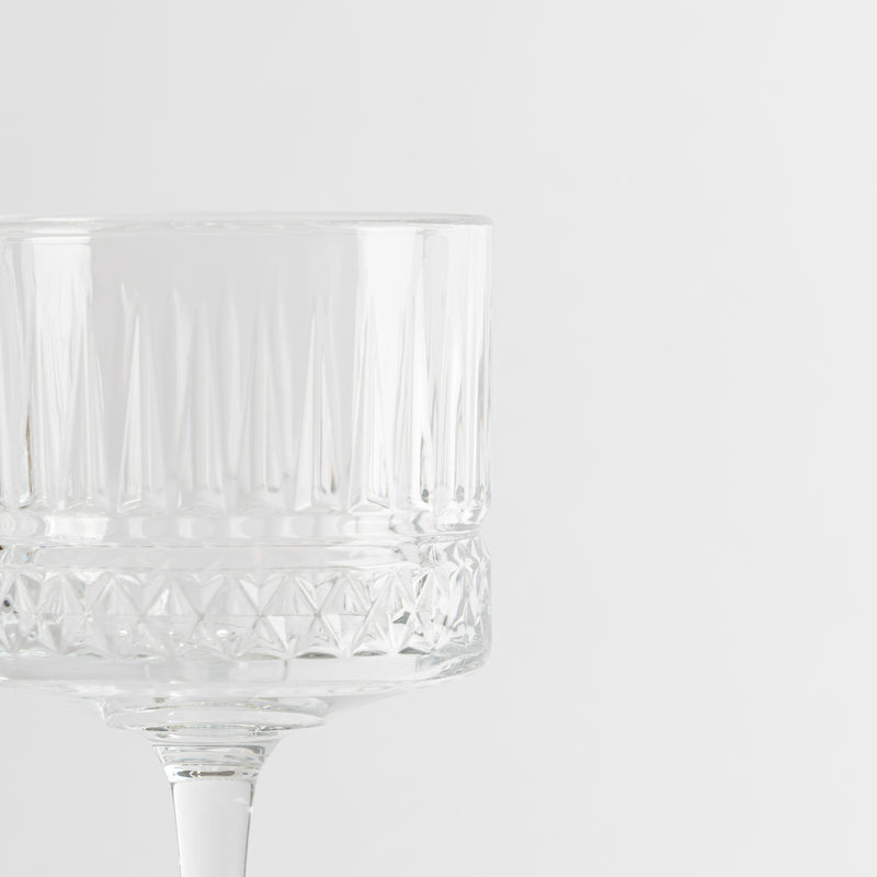 Copa de vidrio transparente con motivos geométricos sobre fondo blanco minimalista
