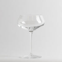 Verre transparent en verre avec tige fine et large coupe basse sur fond blanc