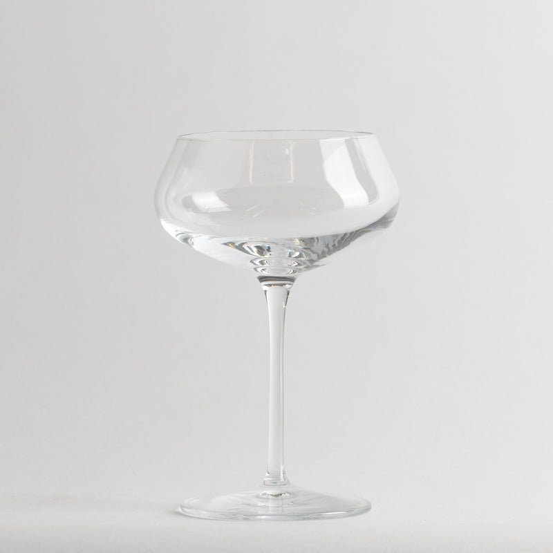 Verre transparent en verre avec tige fine et large coupe basse sur fond blanc