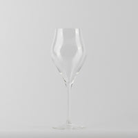 Transparent glass wine glass with thin stem and round base on uniform light grey background.