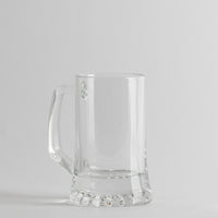Transparante glazen beker met manico, cilindrische vorm met thick basis, lichtgrijze achtergropd.