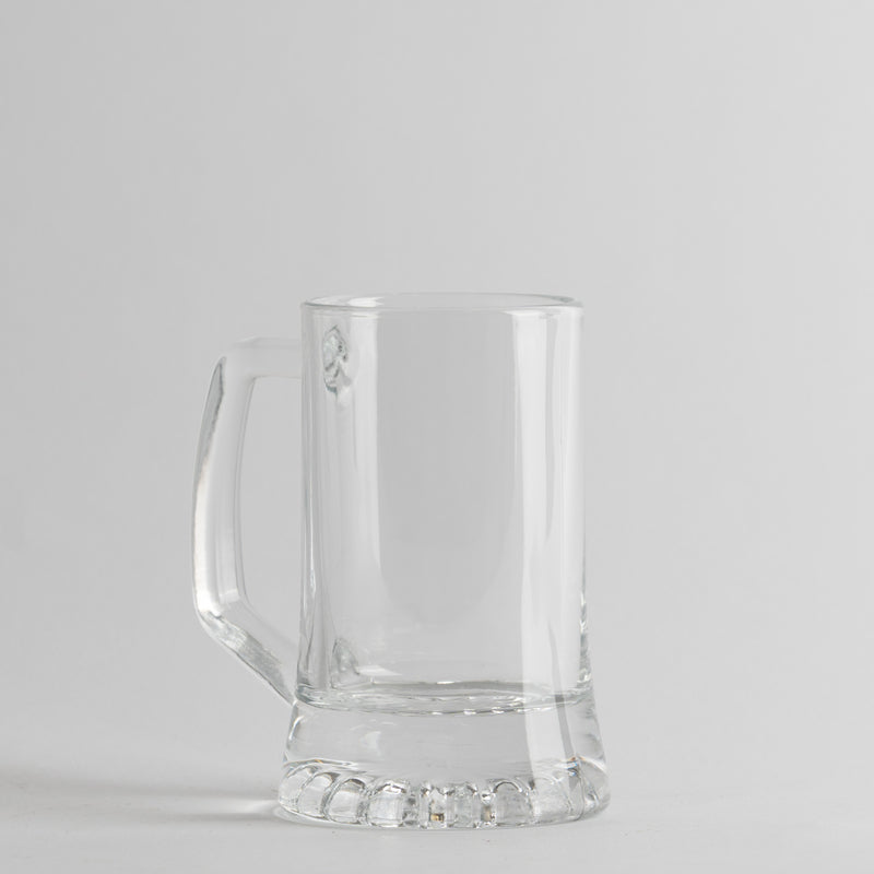 Transparante glazen beker met manico, cilindrische vorm met thick basis, lichtgrijze achtergropd.