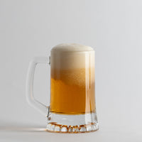Transparante glazen bierpul met gouden bier en wit schuim op lichtgrijze achtergrond