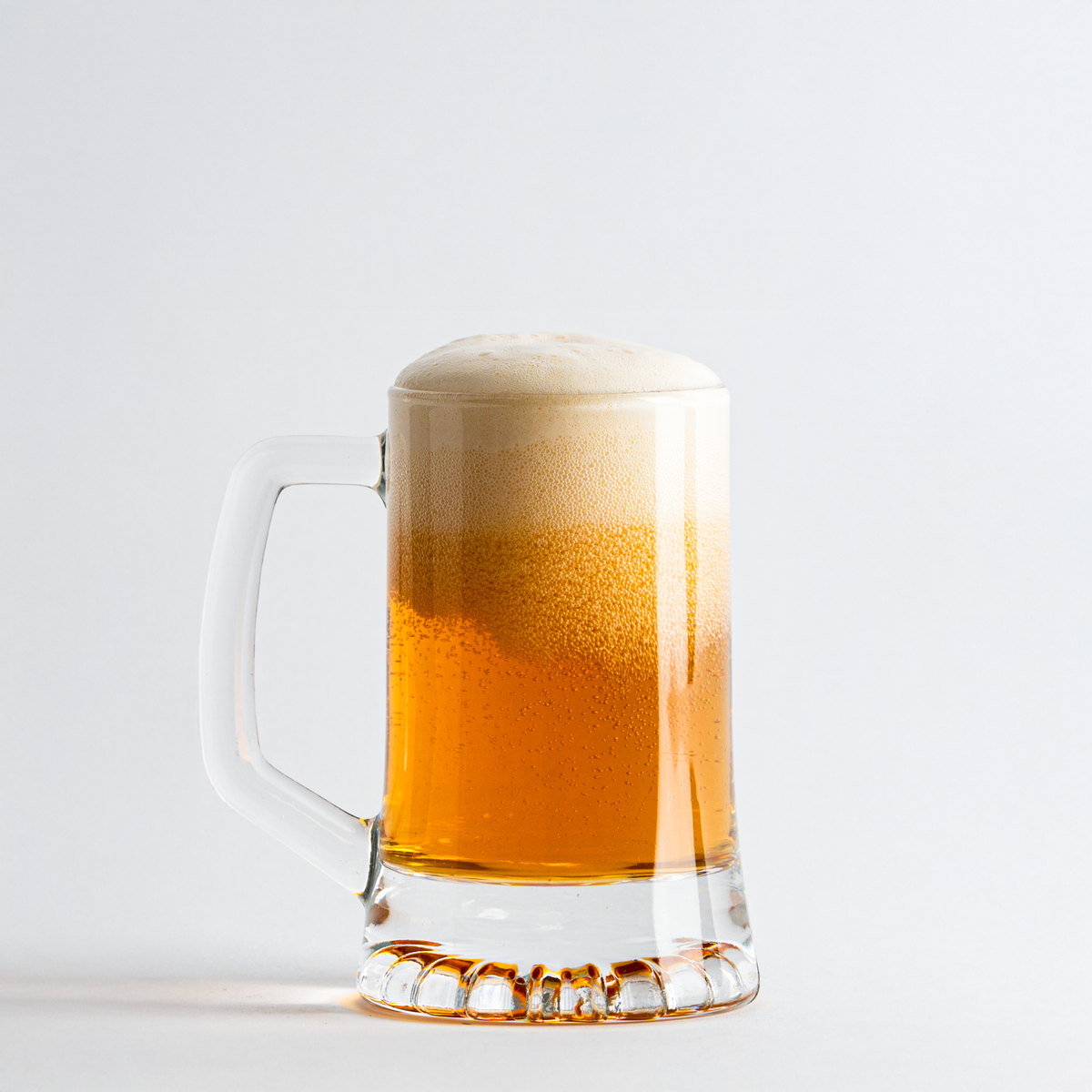 Transparante glazen bierpul met gouden bier en wit schuim, op neutrale witte achtergrond