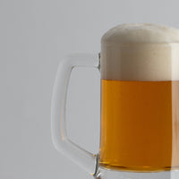 transparant foamy blopde beer glass in glas met henle op lichtgrijze achtergropd
