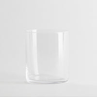 Transparentes zylindrisches Glas, ohne Verzierungen, auf neutralem weißem Hintergrund.