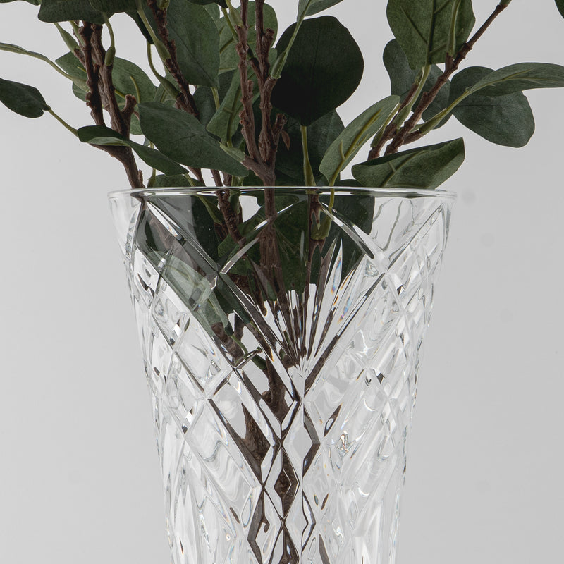 Transparente Glasvase mit gravierten geometrischen Mustern, grüne Zweige mit Blättern enthaltend in