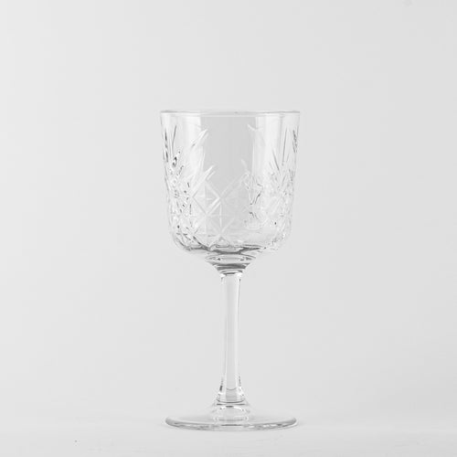 Transparentes Glas-Weinglas mit dekorativen geometrischen Gravuren auf einheitlichem weißem Hintergrund.