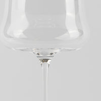 Transparent glass with thin stem on light grey background