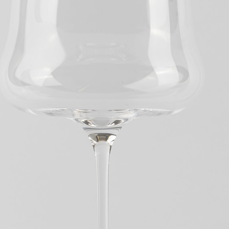 Transparent glass with thin stem on light grey background