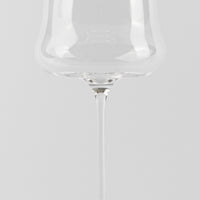 Transparent glass wine glass with thin stem, uniform white background and surface