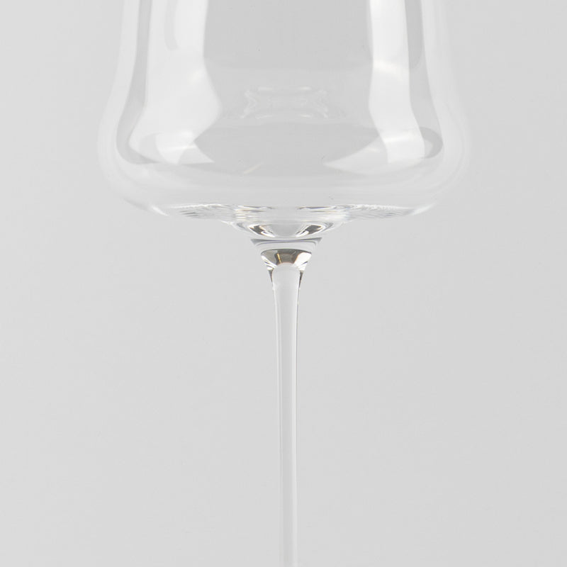 Transparent glass wine glass with thin stem, uniform white background and surface