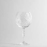 Transluzentes transparentes Glas-Weinglas mit dekorativen Gravuren auf weißem Hintergrund