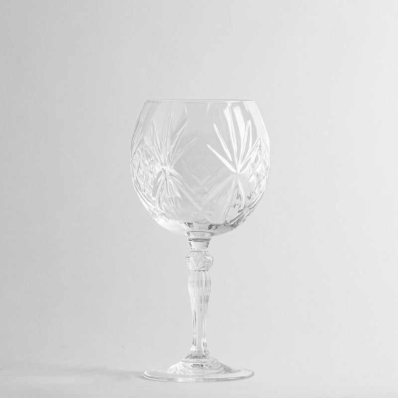 Transluzentes transparentes Glas-Weinglas mit dekorativen Gravuren auf weißem Hintergrund