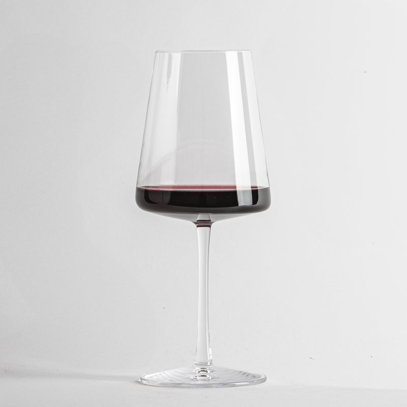 bicchiere di vetro trasparente a forma conica con vino rosso su sfondo bianco uniforme
