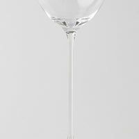 Transparante glazen wijnglas met dunne steel op uniforme lichtgrijze achtergrond