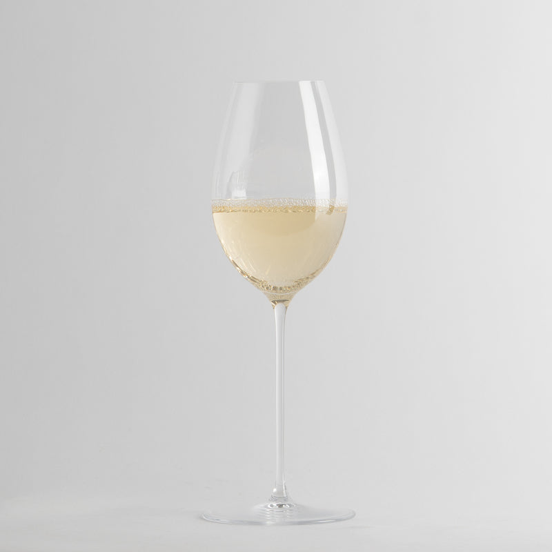 Transparant wijnglas met witte wijn en bellen op minimalistische lichtgrijze achtergrond