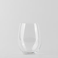 Transparentes stielfreies Glas mit runder Basis und leicht gebogenen Wänden auf hellgrauem Hintergrund