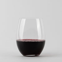 Transparentes stielfreies Glas mit dunkelrotem Wein auf weißem Hintergrund.