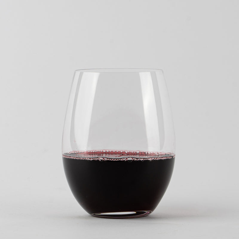 Transparentes stielfreies Glas mit dunkelrotem Wein auf weißem Hintergrund.