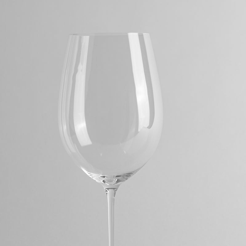 Copa de vino transparente de vidrio liso sobre fondo claro uniforme.