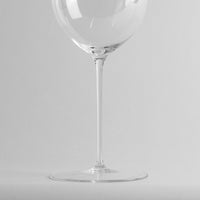 Copa de vino transparente de vidrio con tallo fino sobre fondo gris claro