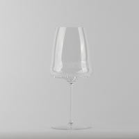 Calice trasparente in vetro con gambo lungo e base tonda, su sfondo grigio uniforme.