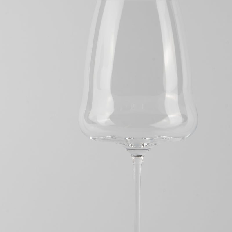bicchiere da vino trasparente in vetro con gambo sottile su sfondo grigio chiaro